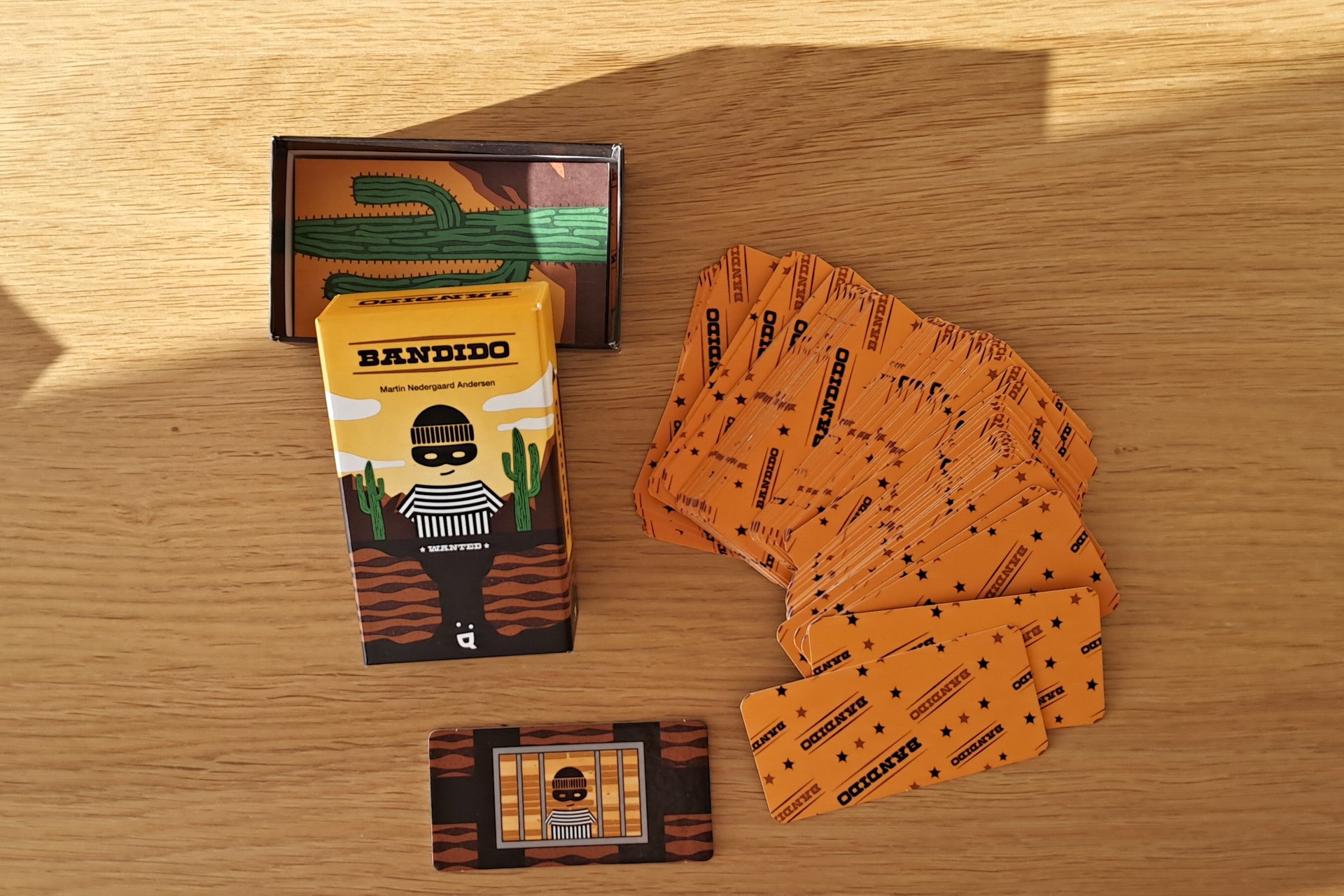 Bandido card game box, all the cards, and the mega card showing six exits