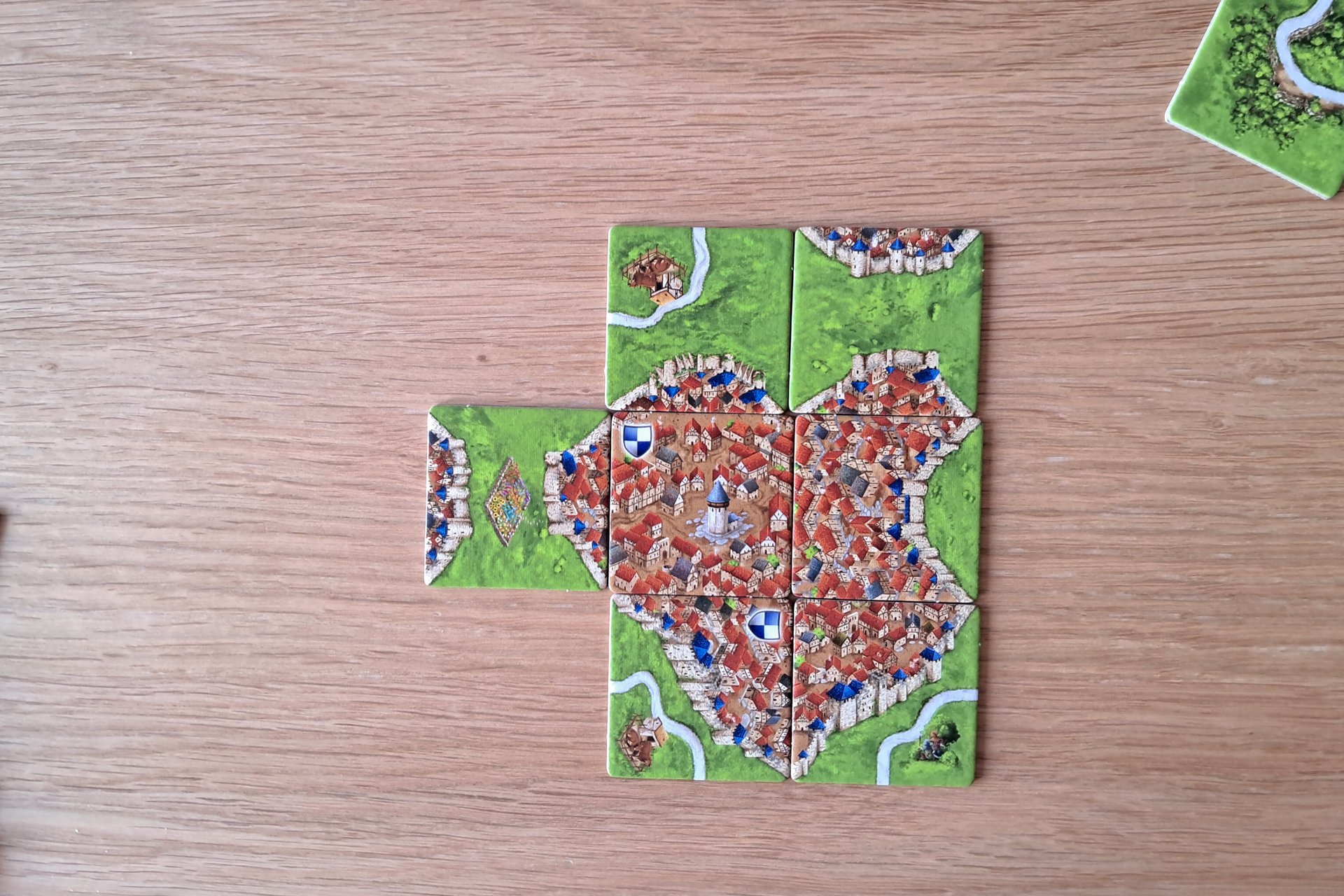 Photo of a Carcassonne board game showing a completed city made from seven connected tiles