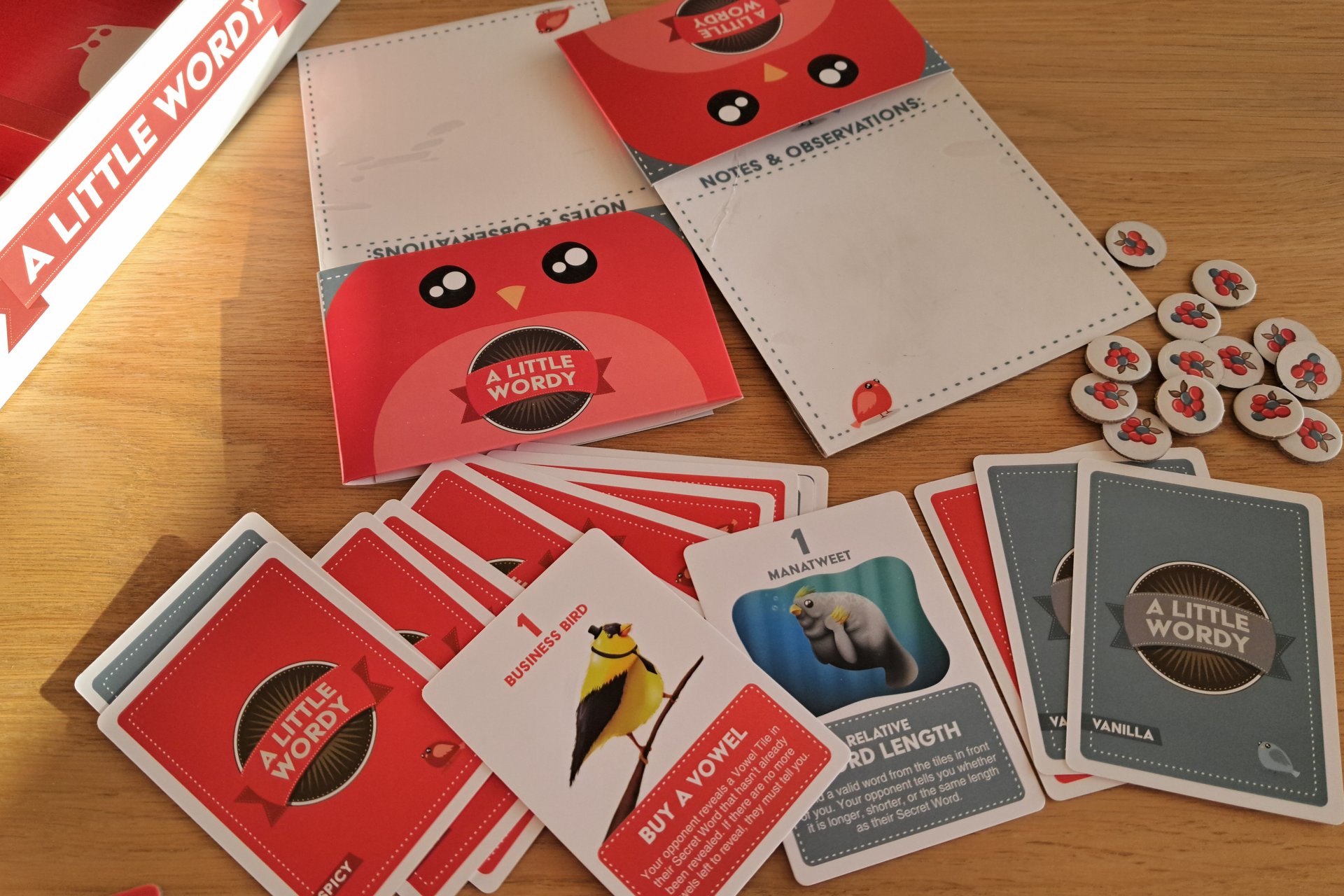 The A Little Wordy game setup showing the boards, clue cards, and berry tokens on the table.