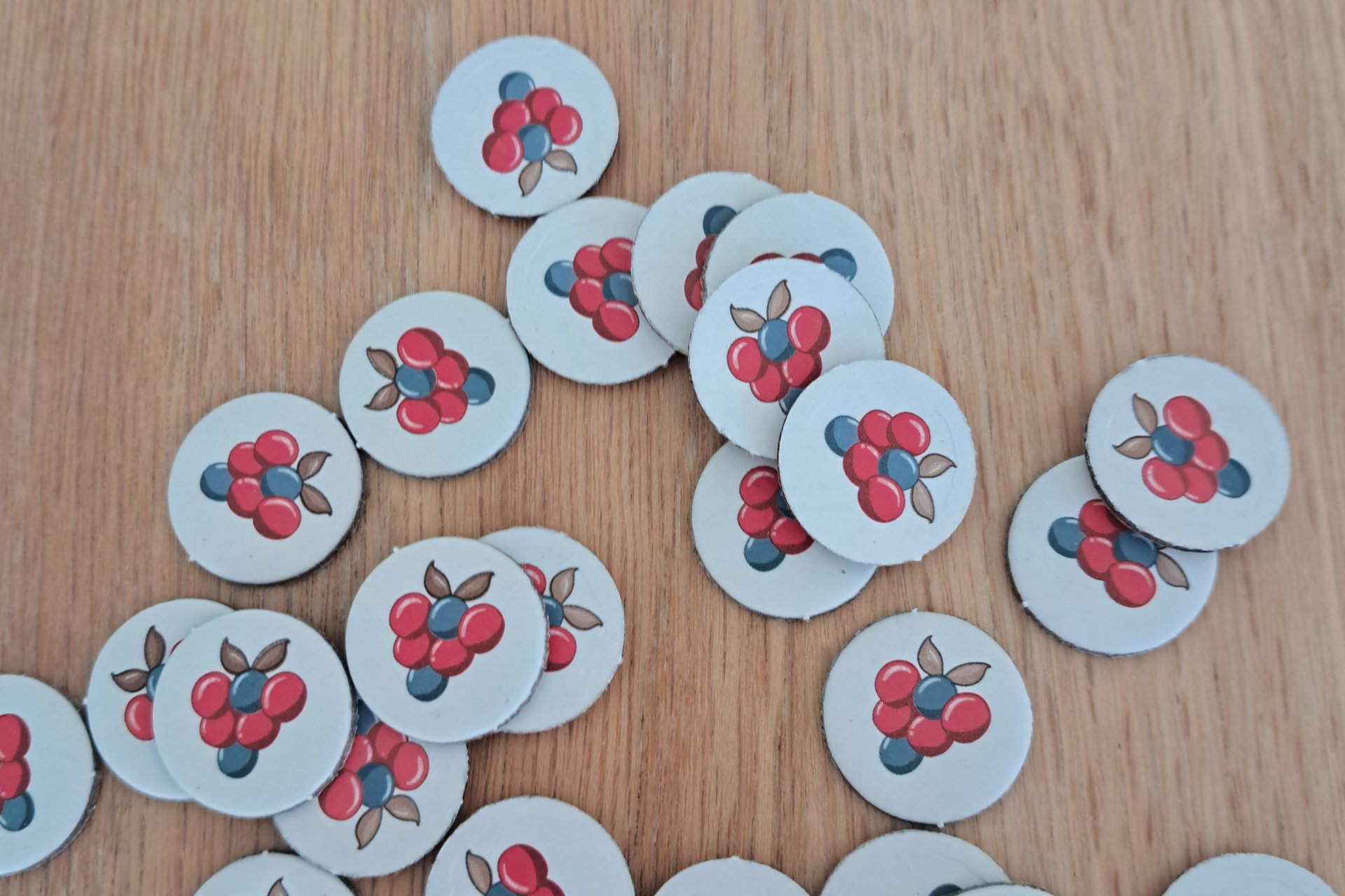 A close up of several berry tokens from A Little Wordy scattered on the table.