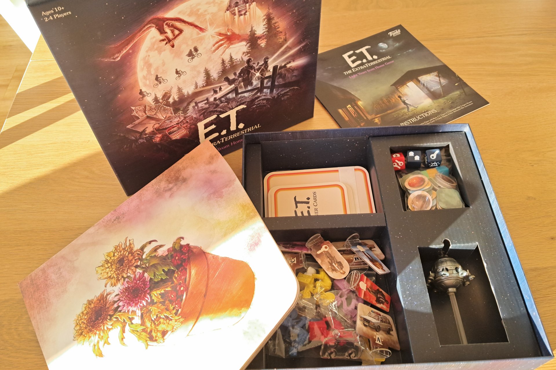 Opened box of the E.T. The Extra Terrestrial Light Years From Home board game. The photo shows the game board, the rulebook, and the inner box containing all the components (cards, tokens, figures).