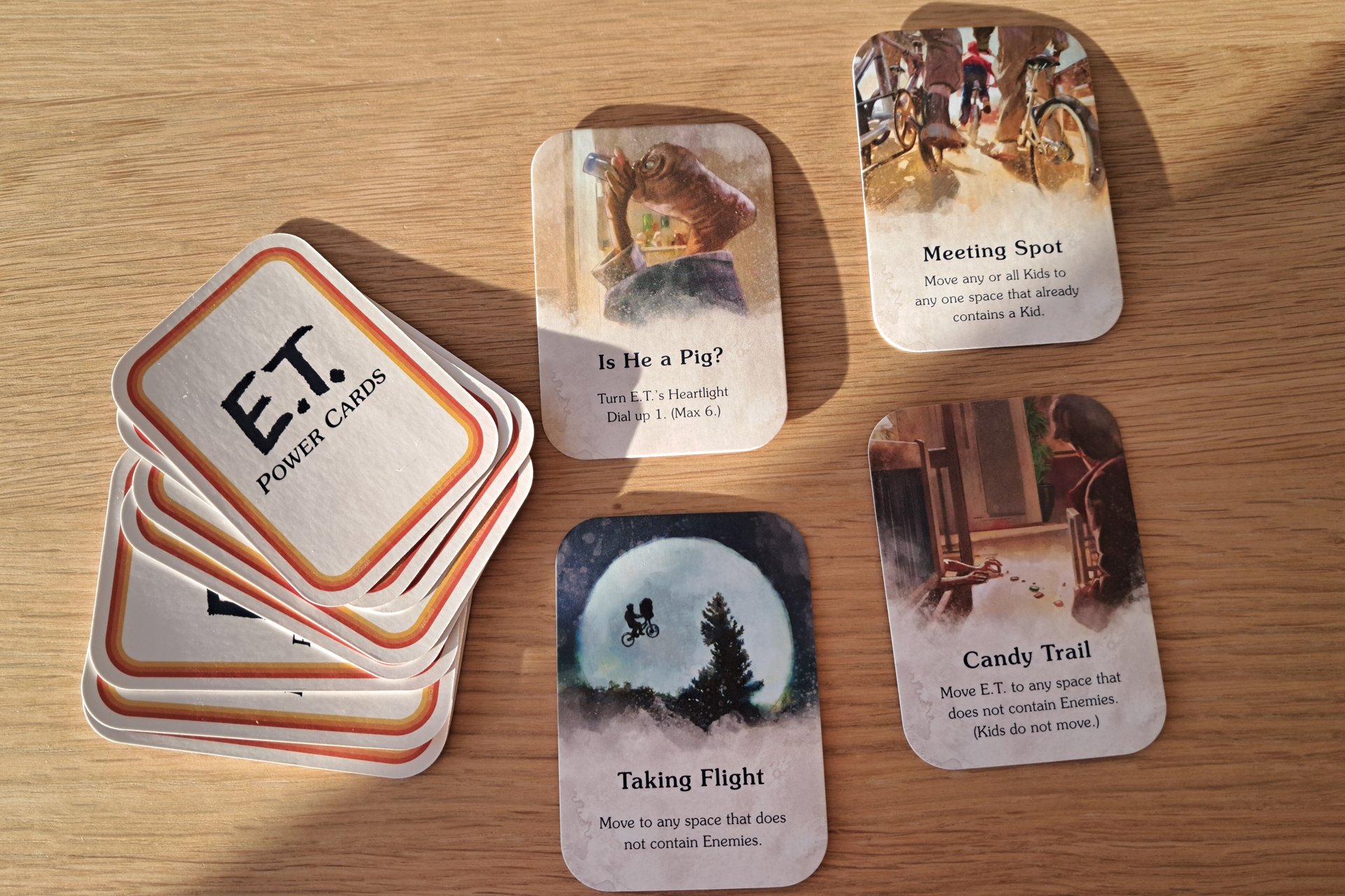 Photo of the E.T. The Extra Terrestrial Light Years From Home game cards. Four E.T. Power cards are displayed on the table with the remaining cards arranged beside them.
