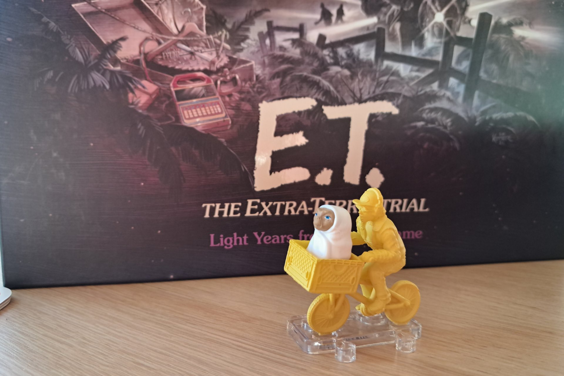 A yellow figure of a child on a bicycle, with E.T. in the front basket.